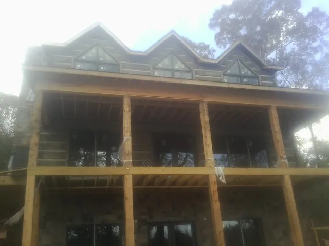 Dormers and porch framing on a large log home under construction — Roof Coating work by our crew in Sunbury