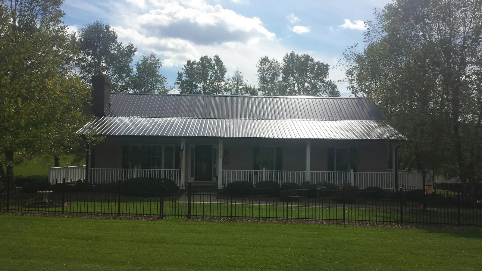 Gray metal roof on a brick ranch with a full width front porch — Gutter Guard Installation work by our crew in Sunbury