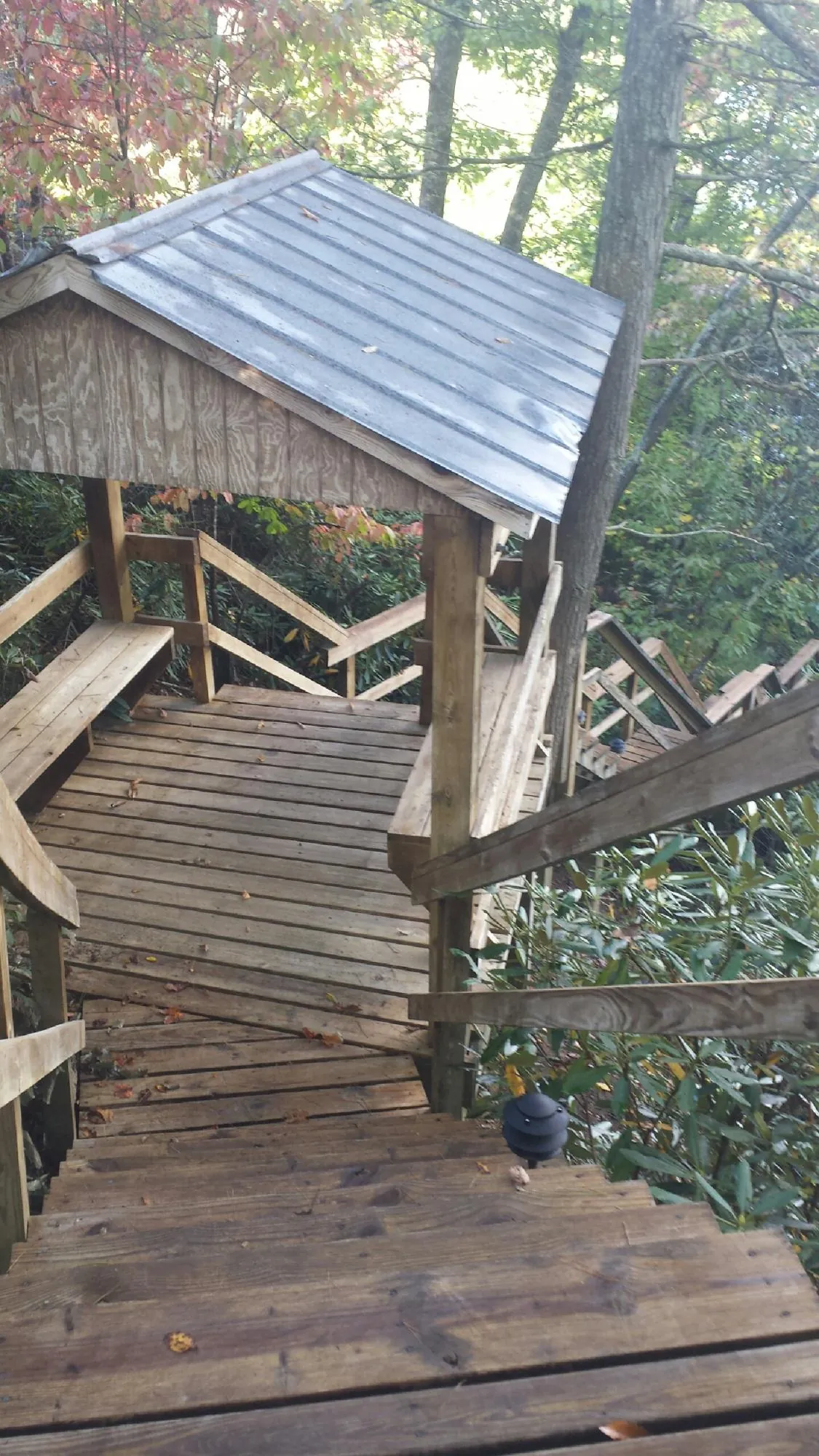 Metal roofed shelter over wooden steps on a wooded walkway — Skylight Repair & Installation work by our crew in Sunbury