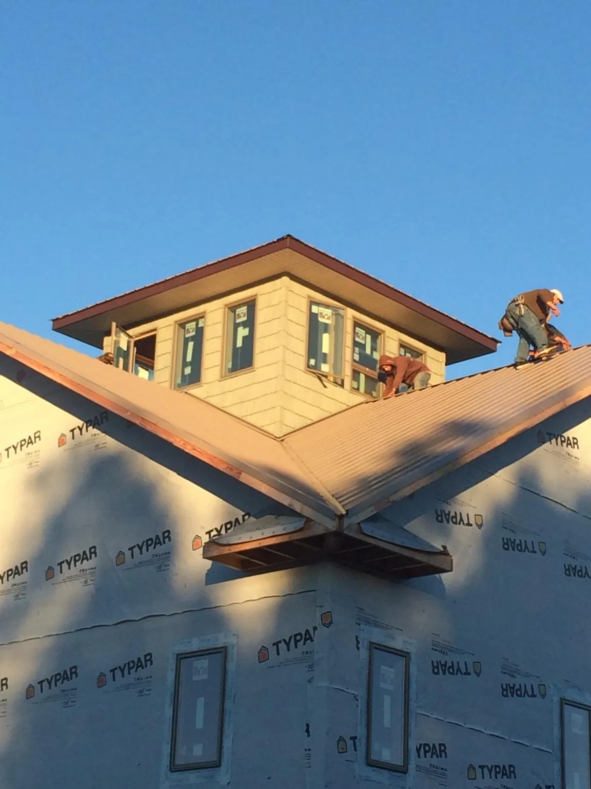 Roofers working around a rooftop cupola on a new metal roof at sunset — Roof Waterproofing in Sunbury by Roofing Brothers